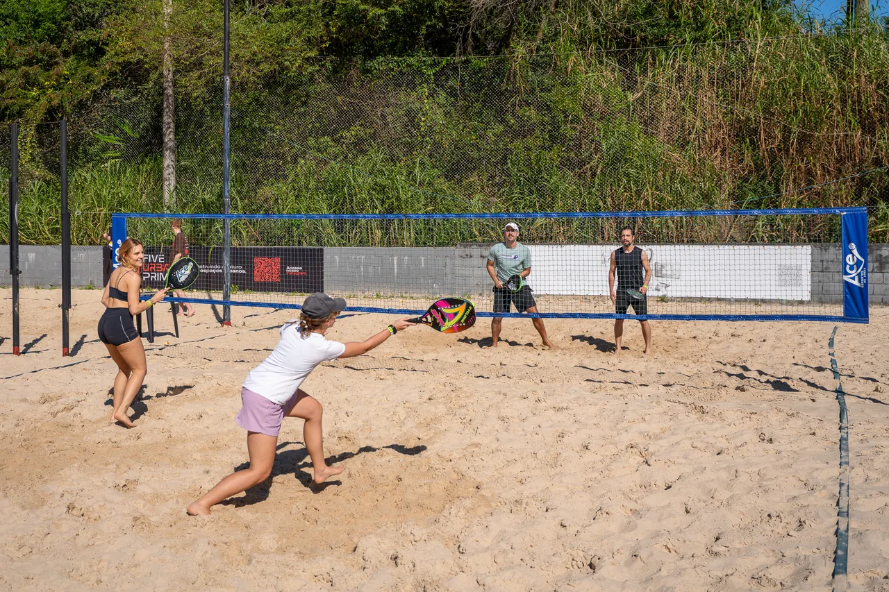 Una jugadora se estira para devolver la pelota en beach tennis.