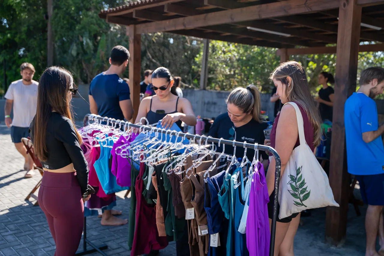 Participantes conversan junto a un perchero de ropa en el evento.
